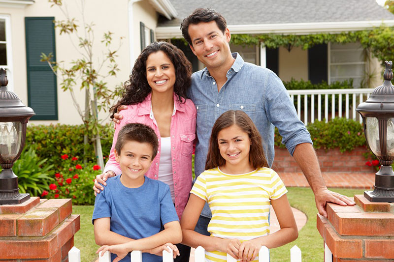 happy family posing in front of a white picket fence